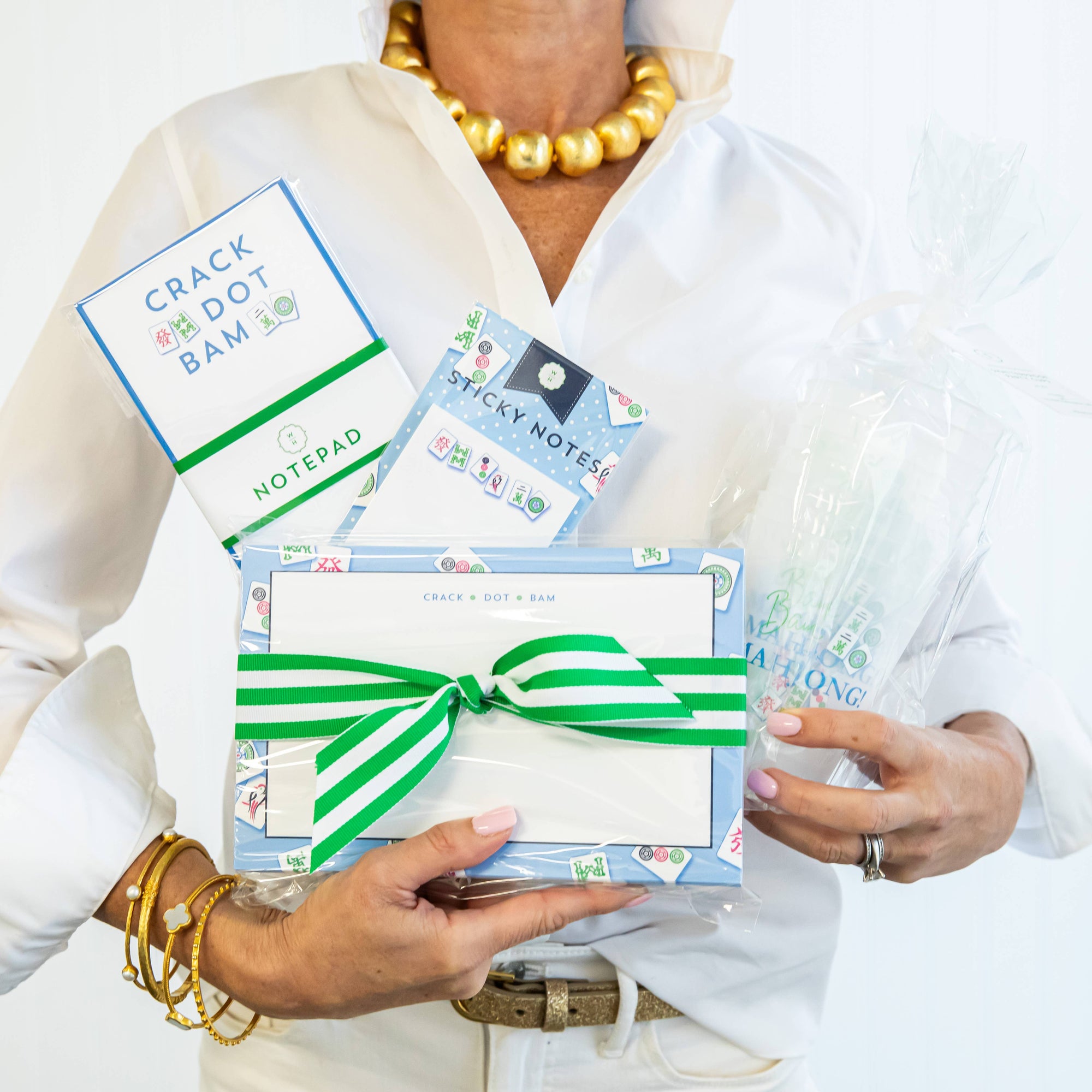 Person holding stationery items including a notepad, sticky notes, and a gift box with a green ribbon.
