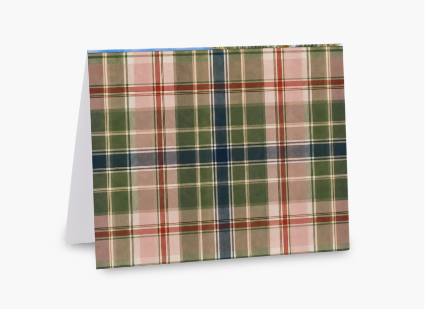 A folded greeting card or paper product standing upright, showing a plaid/tartan pattern with green, pink, navy, red, and beige stripes on a white background.
