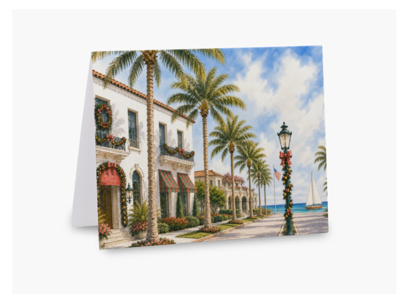 A folded greeting card featuring a painted tropical coastal street scene with white buildings, palm trees, a blue sky, and a sailboat, shown against a light gray background.