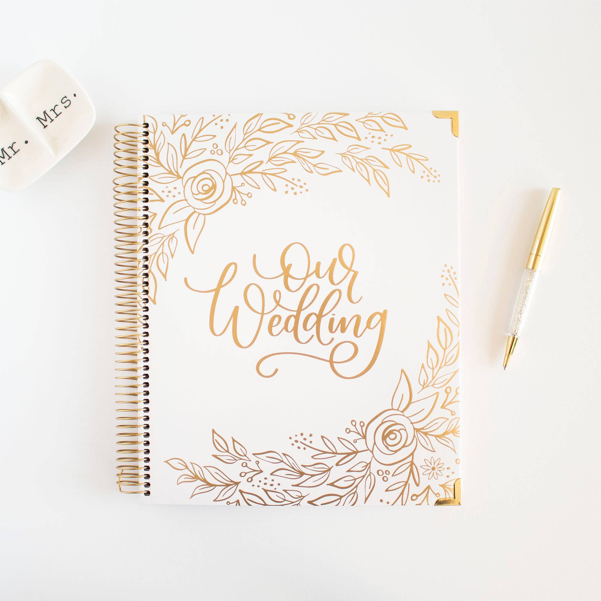 Wedding planner book with gold floral design and 'Our Wedding' text on a white background